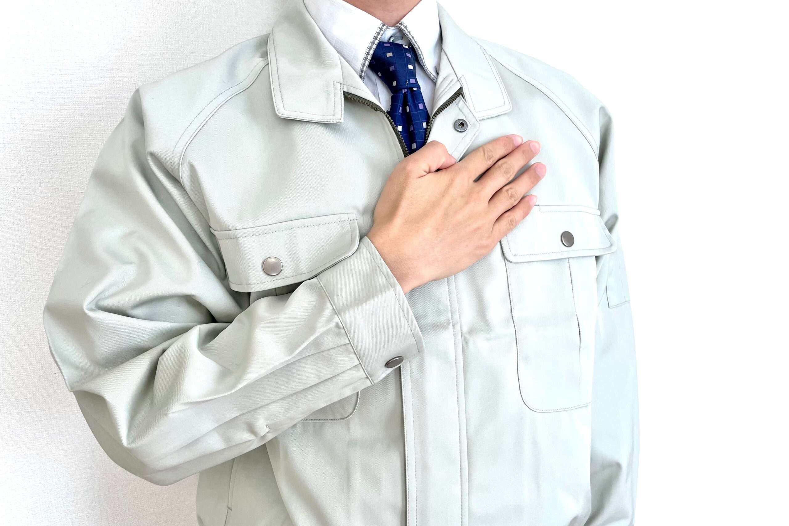 胸に手を添える作業服姿の人物