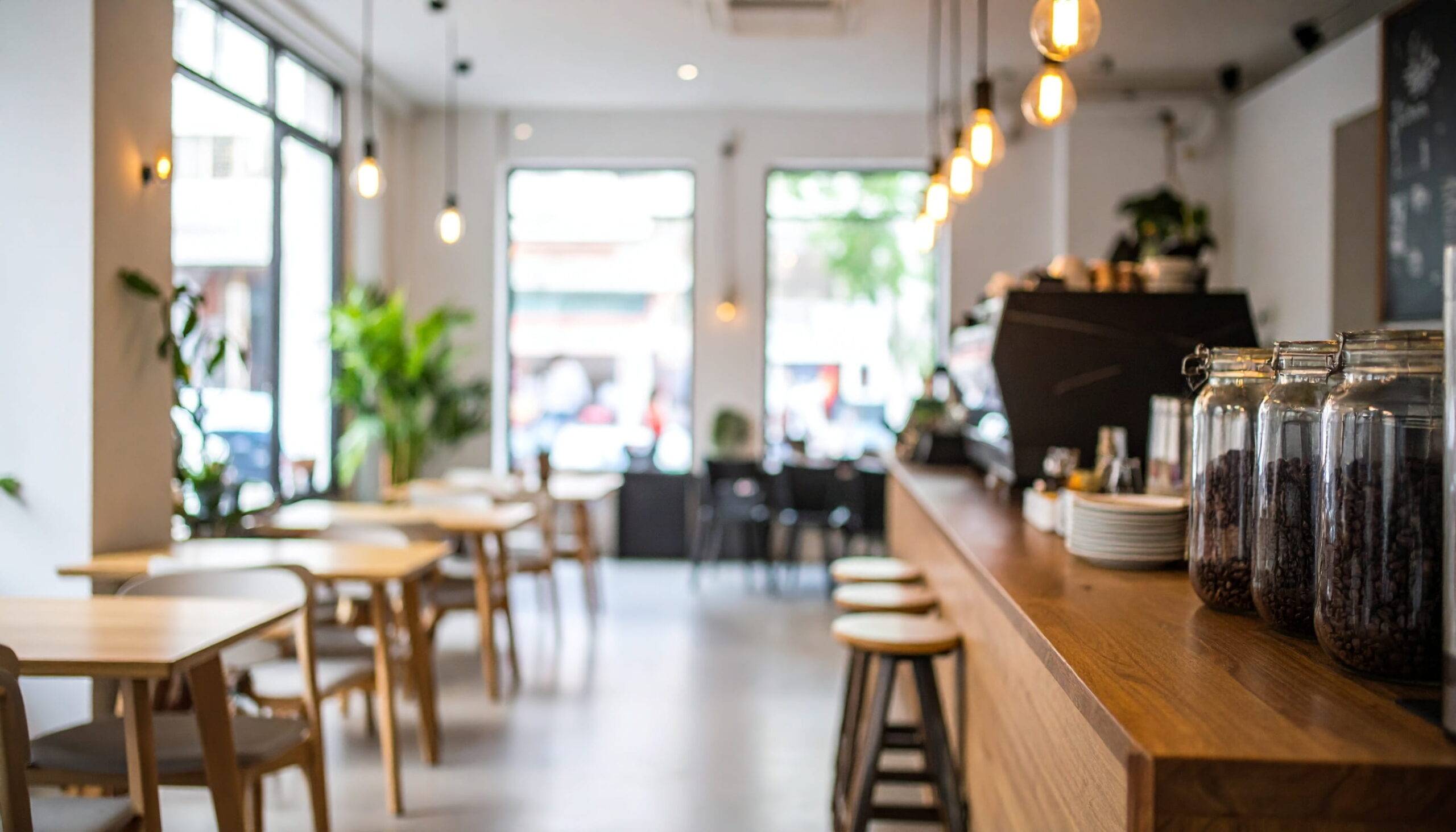 大きな窓から光が差し込み、木製カウンターとテーブル席が並ぶカフェの店内